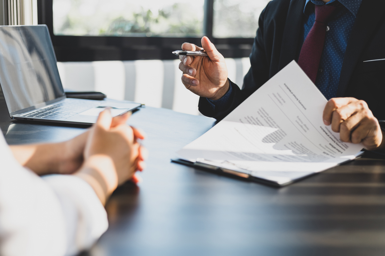Businessman in suit in his office showing an insurance policy and pointing with a pen where the policyholder must to sign Insurance agent presentation and consulting insurance detail to customer